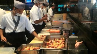 BANGKOK, THAILAND - 26 ARALIK, 2017: Siam Paragon 'daki Japon restoranında şefler. Beyaz üniformalı Asyalı adamlar profesyonel bir mutfakta deniz ürünleri kesiyor..
