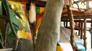 Jamaika keneviri rasta marihuana reggae barı gevşetiyorum. Tropikal yaz plajında, ağaç dalları ve sazlıktan. Sarı, kırmızı ve yeşil renkli Rastafarian bayrakları ve Bob Marley.