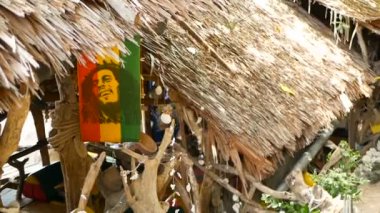 Jamaika keneviri rasta marihuana reggae barı gevşetiyorum. Tropikal yaz plajında, ağaç dalları ve sazlıktan. Sarı, kırmızı ve yeşil renkli Rastafarian bayrakları ve Bob Marley.