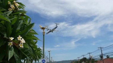 KOH SAMUI ADASI, THAILAND - 23 Haziran 2019 Tropikal kasabanın ana caddesine inen uçak. Bangkok havaalanına giden uçaklar, egzotik turistik tatil beldeleri. Motosikletli Taylandlılar