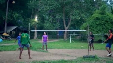 ANG THAILAND - 9 HAZİRAN 2019 Taylandlı gençler parkta sepak oynuyorlar. Yerel yerleşim bölgesindeki yeşil ağaçlara karşı voleybol oynayan bir grup adam. Geleneksel ulusal spor oyunu.