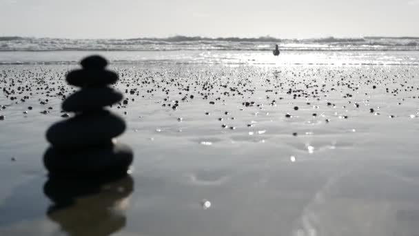 Kamień balansujący na plaży oceanicznej, kamienie układające się przy morskich falach wodnych. Piramida kamieni na piaszczystym brzegu — Wideo stockowe