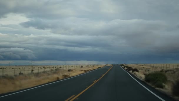 Conducción de automóviles, viaje por carretera en California, EE.UU., vista desde el coche. Hacer autostop viajando por Estados Unidos. Autopista, montañas y cielo nublado y dramático antes de la tormenta de lluvia. Una ruta panorámica americana. Punto de vista del pasajero — Vídeos de Stock