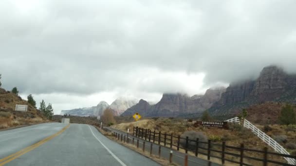 Road trip, auto à Zion Canyon, Utah, États-Unis. Voyage en auto-stop en Amérique, voyage d'automne. Falaises raides extraterrestres rouges, pluie et arbres nus. Météo brumeuse et atmosphère d'automne calme. Vue de la voiture — Video