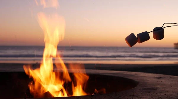 Campfire pit in California USA. Camp fire on ocean sea beach, roasting toast marshmallow on bonfire.