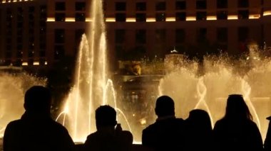 LAS VEGAS, NEVADA USA - 13 Aralık 2019: İnsanlar geceleri Bellagio Fountain müzik performansına bakıyor. Karşıt siluetler ve parlayan dans eden su sıçramaları. Kumar şehrinde eğlence şovu.