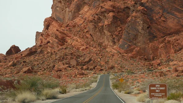 Roadtrip, Autofahren in Valley of Fire, Las Vegas, Nevada, USA. Per Anhalter in Amerika unterwegs, Autobahnfahrt. Rote außerirdische Felsformation, Wüste Mojave sieht aus wie Mars. Blick aus dem Auto — Stockfoto