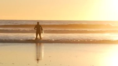 Okyanus Kenarı, Kaliforniya ABD - 27 Aralık 2019: Sörfçü silueti, Pasifik Okyanus Sahili, su dalgaları ve gün batımı. Tropik sahil şeridi, sahil tatil beldesi. İnsanlar spor olsun diye sörf yapmaktan hoşlanıyor..