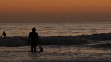 Okyanus Kenarı, Kaliforniya ABD - 16 Şubat 2020: Sörfçü silueti, Pasifik Okyanus Sahili, su dalgaları ve gün batımı. Tropik sahil şeridi, sahil tatil beldesi. İnsanlar spor olsun diye sörf yapmaktan hoşlanıyor..