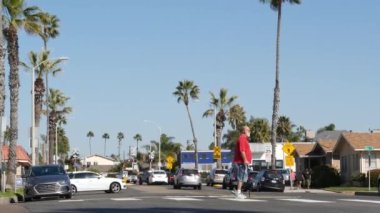 Oceanside, California USA - 8 Şubat 2020: Palmiye ağaçlarıyla bisiklet süren kişi. Bisikletli bisiklet, sağlıklı yaşam tarzı spor hobisi. Pacific Surfliner Amtrak treni yakınındaki insanlar. Demiryolu geçidi.