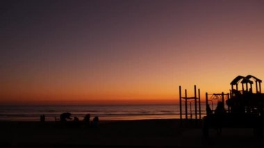 Oceanside, California USA - 8 Şubat 2020: bbq kamp ateşi yakan insanların silueti. Pasifik Okyanusu kıyısında şöminesi olan barbekü için sahil bölgesi. Gün batımında barbekü için şenlik ateşi.