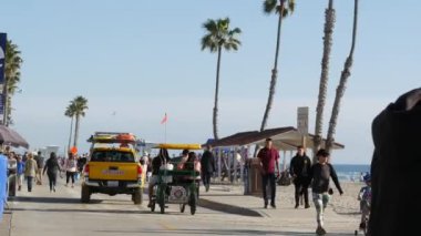 Oceanside, California USA -16 Şubat 2020: İnsanlar geziniyor, deniz kenarında geziniyor, rıhtım kıyısında sahil kenarında rıhtımda yürüyor. Los Angeles yakınlarında okyanus kıyısındaki tatil beldesi. Cankurtaran arabası, surrey bisiklet..