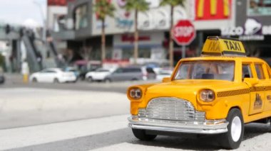 LAS VEGAS, NEVADA USA - 7 MAR 2020: Harmon Bulvarı köşesindeki sarı boş taksi. Küçük bir eski araba modeli. Amerikan alışveriş merkezlerine karşı taşımacılık sembolü olarak küçük ikonik otomobil oyuncağı.