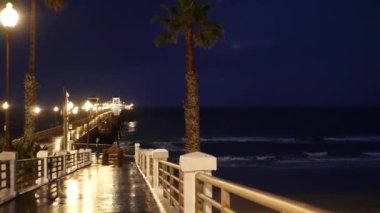 Yağmur damlaları, Oceanside California USA 'da akşam. İskele, alacakaranlıkta avuçlar. Işığın yansıması.