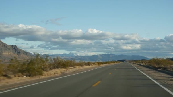 ロードトリップ、デスバレーからラスベガス、ネバダ州米国への自動運転。アメリカでのヒッチハイキング。高速道路の旅、劇的な雰囲気、雲、山とモハベ砂漠の荒野。車からの眺め — ストック動画