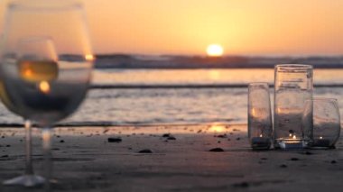 Camdaki mum ışıkları, okyanus dalgalarıyla romantik plaj tarihleri, yaz denizi. Kumdaki mum ışığı..