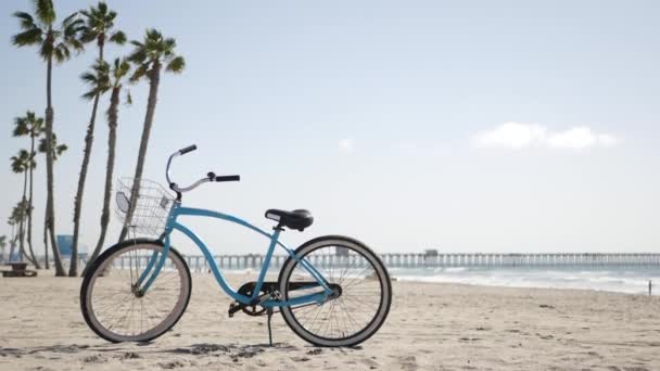 カリフォルニア州海岸の海のビーチで自転車クルーザーバイク。夏のサイクル、ライフガード小屋とヤシの木 — ストック動画