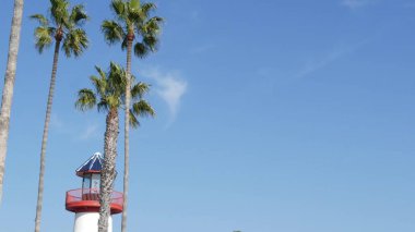 Deniz feneri, palmiye ağaçları ve mavi gökyüzü. Kırmızı ve beyaz fener. Liman köyü. Kaliforniya ABD