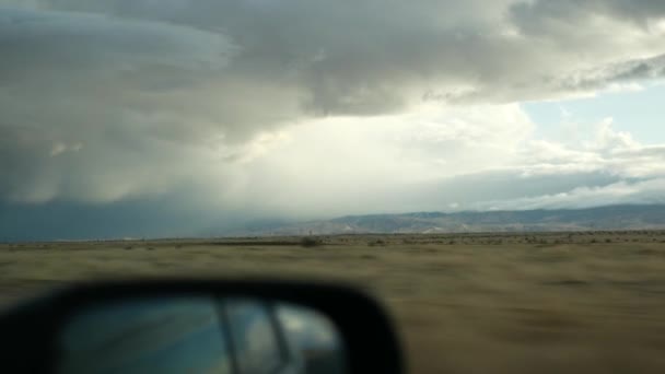 Conducción de automóviles, viaje por carretera en California, EE.UU., vista desde el coche. Hacer autostop viajando por Estados Unidos. Autopista, montañas y cielo nublado y dramático antes de la tormenta de lluvia. Una ruta panorámica americana. Punto de vista del pasajero — Vídeo de stock