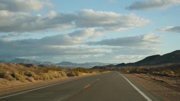 Viaje por carretera, conduciendo auto desde Death Valley a Las Vegas, Nevada, EE.UU. Hacer autostop viajando por América. Viaje por carretera, atmósfera dramática, montaña al atardecer y desierto de Mojave. Vista desde el coche — Vídeo de stock