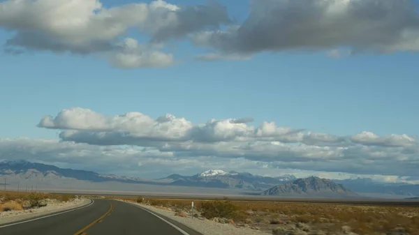 Road trip, driving auto from Death Valley to Las Vegas, Nevada USA. Hitchhiking traveling in America. Highway journey, dramatic atmosphere, cloud, mountain and Mojave desert wilderness. View from car — Stock Photo, Image