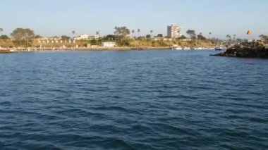 Yelkenli tekne ya da yattan deniz suyunun gün batımı manzarası, okyanus kıyısı, Kaliforniya 'da yaz tatili. Limanda şehir tabelası, yat limanında kısa mektuplar. Pasifik Okyanusu kıyısı, balina izleme turu.