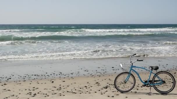 Велосипедный крейсер на берегу океана Калифорнийского побережья США. Летний голубой цикл, песок и волна воды — стоковое видео