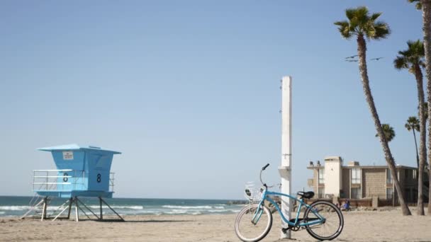 Vélo de croisière à vélo par la plage de l'océan Californie côte États-Unis. Côte de mer d'été. Cycle par tour de sauveteur — Video