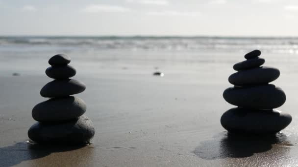 Rock balancing on ocean beach, stones stacking by sea water waves. Pyramid of pebbles on sandy shore — Stock Video