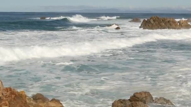 Ondas e rochas oceânicas, Monterey, norte da Califórnia, EUA. 17 milhas de carro perto de Big Sur, resort turístico de golfe à beira-mar na Pacific Coast Highway. Espalhando água e brisa do mar da praia de seixos. Viagem de carro — Vídeo de Stock