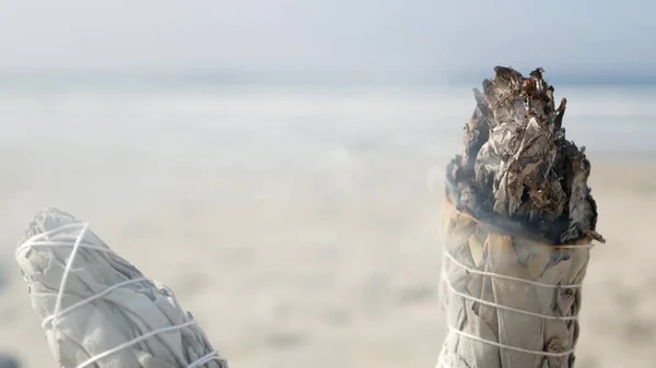 Humo de salvia blanca, quemadura de palo de mancha. Meditación de manchas de aroma en la playa del océano, olas de agua de mar. — Foto de Stock