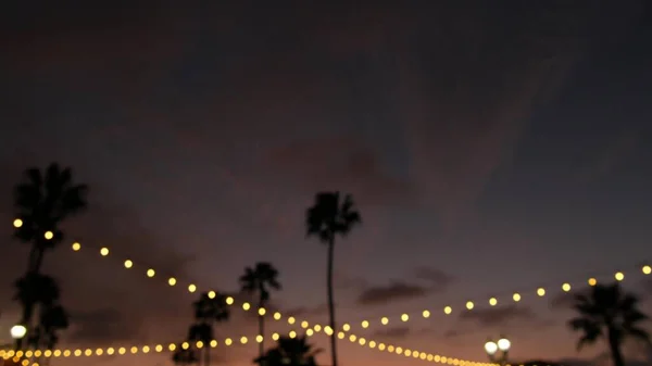 Elektromos koszorú, pálmafák California USA. Tengerparti naplemente, tengerparti szürkületi ég. Los Angeles-i fények. — Stock Fotó