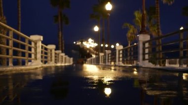 Yağmur damlaları, Oceanside California USA 'da akşam. İskele, alacakaranlıkta avuçlar. Işığın yansıması.