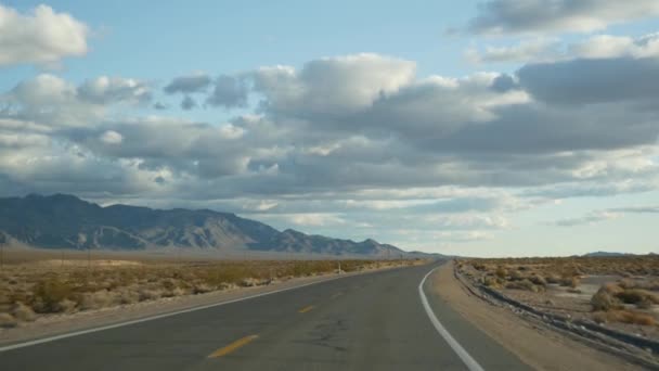 开车从死谷到美国内华达州拉斯维加斯的公路旅行。搭便车在美国旅行。公路旅行，戏剧性的氛围，云彩，高山和莫哈韦沙漠荒原。从车上看 — 图库视频影像