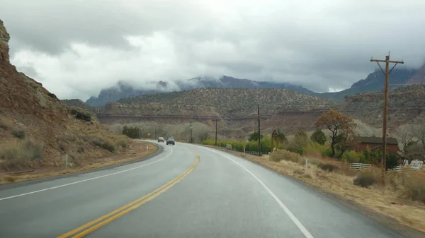 Roadtrip, Autofahren in Zion Canyon, Utah, USA. Per Anhalter durch Amerika, Herbstreise. Rote außerirdische steile Klippen, Regen und kahle Bäume. Nebel und ruhige Herbststimmung. Blick aus dem Auto — Stockfoto