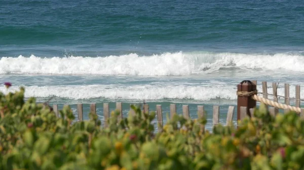 Valuri mari de maree pe plajă, California, SUA. Coasta oceanului Pacific, gard picket pe malul mării . — Fotografie, imagine de stoc