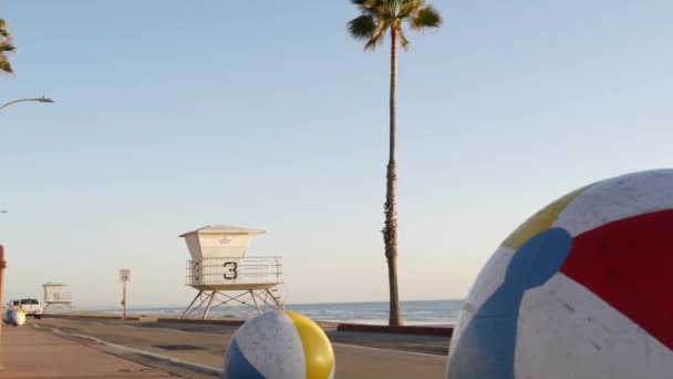 Ocean beach California USA. Ball, lifeguard tower, life guard watchtower hut, beachfront palm tree. — Stock Video