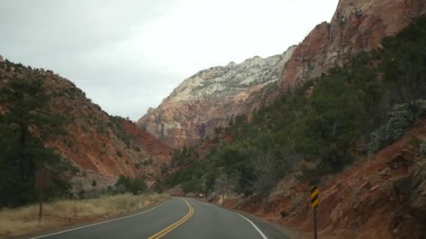 Vägresa, bilkörning i Zion Canyon, Utah, USA. Liftar i Amerika, höstresa. Röda utomjordiska branta klippor, regn och kala träd. Foggy väder och lugn höst atmosfär. Utsikt från bilen — Stockvideo