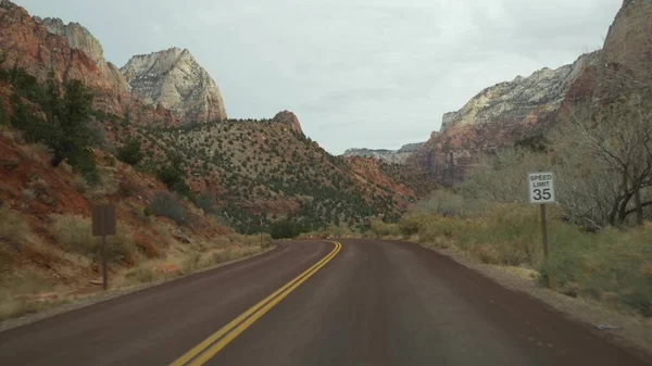 Viaje por carretera, conducción de automóviles en Zion Canyon, Utah, EE.UU. Autoestop viajando por América, viaje de otoño. Acantilados escarpados alienígenas rojos, lluvia y árboles desnudos. Clima brumoso y ambiente tranquilo de otoño. Vista desde el coche — Foto de Stock