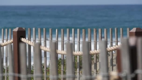 Summer waves on beach, California shoreline USA. Pacific ocean coast, picket fence on sea shore. — Stock Video