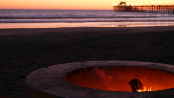 Kampvuurplaats in Californië USA. Kampvuur op schemerstrand, kampvuur vlam door zee watergolven. — Stockvideo