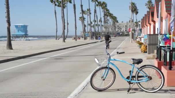 Bicicleta de crucero en bicicleta por la playa del océano, costa de California EE.UU.. Ciclo de verano, cabaña salvavidas y palmera — Vídeo de stock