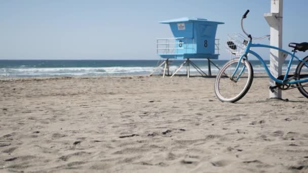 Bicicleta de cruzador de bicicleta pela praia oceânica costa da Califórnia EUA. Costa do mar de verão. Ciclo por torre salva-vidas — Vídeo de Stock