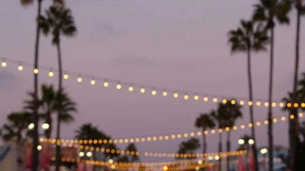 Elektrické věnce, palmy Kalifornie USA. Západ slunce na pláži, soumrak na pobřeží. Los Angeles světla. — Stock fotografie