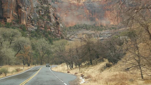 Road trip, auto à Zion Canyon, Utah, États-Unis. Voyage en auto-stop en Amérique, voyage d'automne. Falaises raides extraterrestres rouges, pluie et arbres nus. Météo brumeuse et atmosphère d'automne calme. Vue de la voiture — Photo