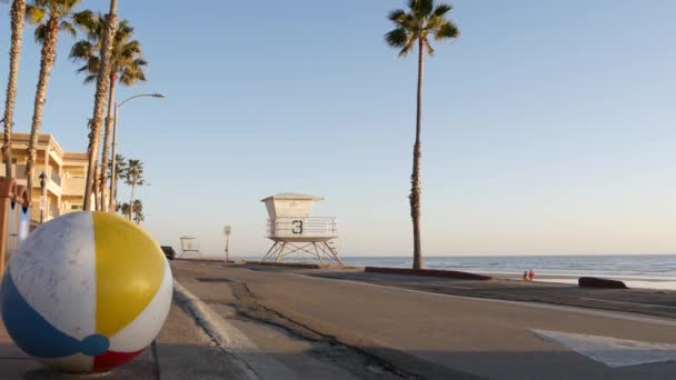 Ocean beach California USA. Míč, věž plavčíka, chata strážné věže, palma u pláže. — Stock video