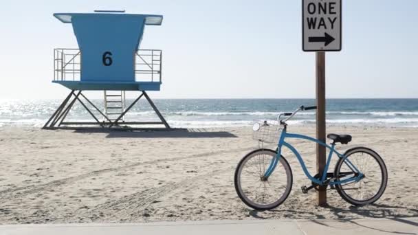 Bicicleta de crucero en bicicleta por la playa del océano, costa de California EE.UU.. Ciclo de verano, torre salvavidas, señal de tráfico — Vídeos de Stock