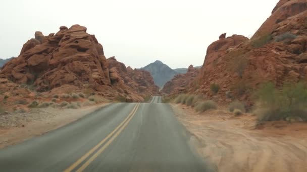 Οδικό ταξίδι, οδήγηση αυτοκινήτου στην Κοιλάδα της Φωτιάς, Λας Βέγκας, Νεβάδα, ΗΠΑ. Βόλτα με ωτοστόπ στην Αμερική, ταξίδι στην εθνική οδό. Κόκκινος εξωγήινος σχηματισμός βράχων. Η έρημος Μοχάβε μοιάζει με τον Άρη. Θέα από αυτοκίνητο — Αρχείο Βίντεο