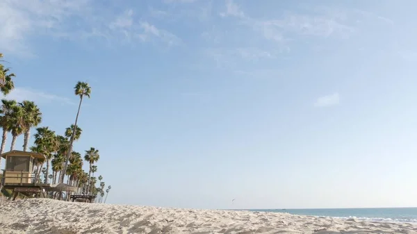 Palmeiras na praia de areia branca, costa marítima oceânica na Califórnia EUA. Torre de salva-vidas, cabana da torre de vigia. — Fotografia de Stock