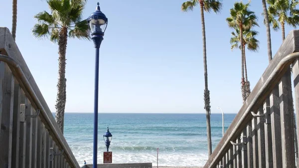 Wooden stairs, beach access in California USA. Coastal stairway, pacific ocean waves and palm trees. — Stock Photo, Image